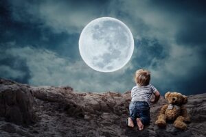 Billede af en dreng og en bamse der kigger på månen fra vuggevise Månebarn